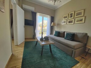 Ein gemütliches Wohnzimmer mit einer Couch, einem Couchtisch und Blick ins Freie durch ein Fenster.
