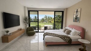 Un dormitorio con cama, televisor, balcón con vistas y una mesita.