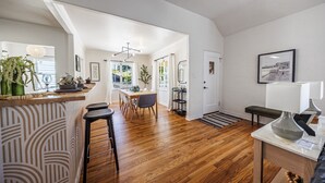 Eine moderne Küche mit Holzboden, einem Essbereich mit Tisch und Stühlen sowie einer Bar mit Hockern.