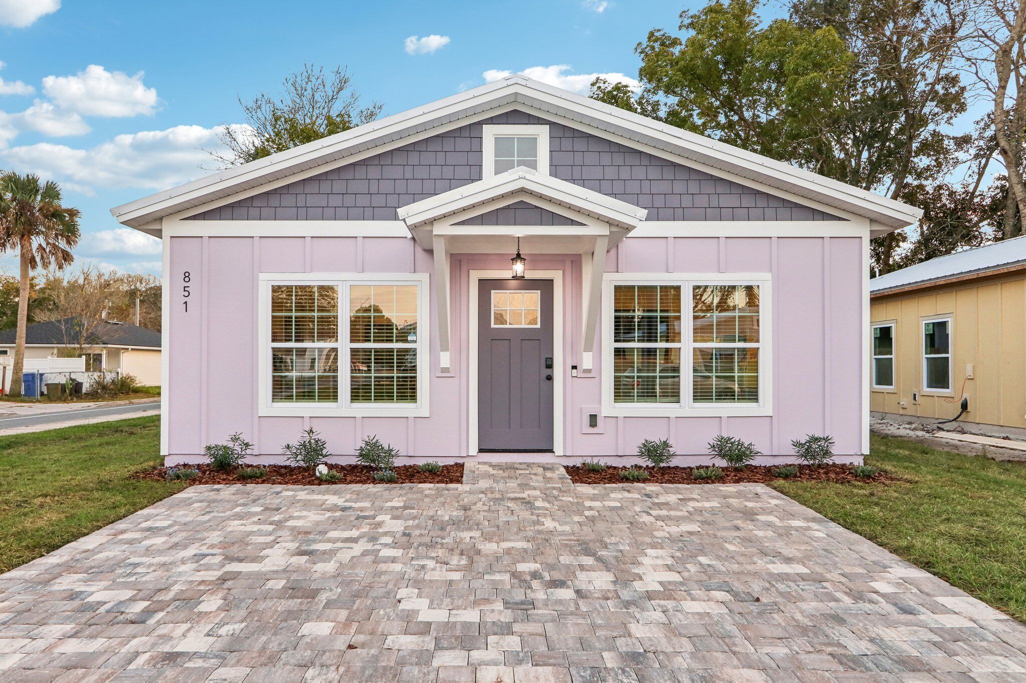 A single-story house with a grey roof, a front door, and two windows on the front facade.