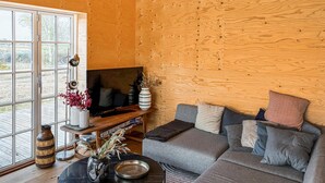 Un accogliente soggiorno con parete in legno, un divano, un tavolino e una televisione.