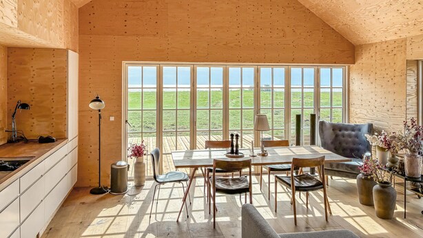 Un interno in legno con zona pranzo, cucina e ampie finestre.