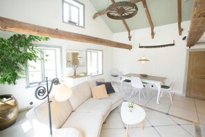 Un salon moderne avec un canapé, une table à manger, des chaises et une grande fenêtre.