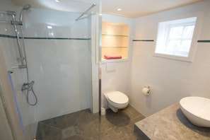 Ein Badezimmer mit Duschkabine, Toilette, Waschbecken und Fenster.