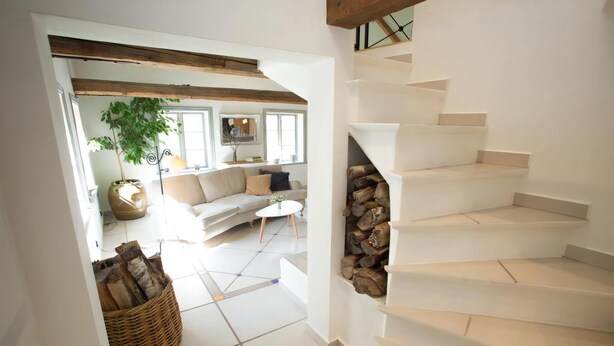 A staircase leading to a loft area with a white interior, a sofa, a coffee table, and a plant. - French countryhouse atmosphere (Vessigebro)