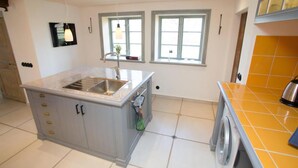 A kitchen with a sink, a washing machine, and a window. - French countryhouse atmosphere (Vessigebro)