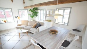 A modern living room with a sofa, dining table, chairs, and a potted plant. - French countryhouse atmosphere (Vessigebro)