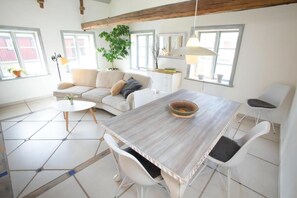 A modern living room with a sofa, dining table, chairs, and a potted plant. - French countryhouse atmosphere (Vessigebro)