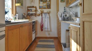 Een keuken met houten kastjes, een spoelbak, een fornuis en een raam.