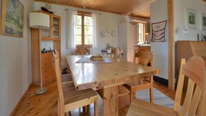 Een houten eettafel met stoelen, een lamp en een koelkast in een kamer met houten plafonds en wanden.