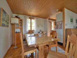 A wooden dining table with chairs, a lamp, and a refrigerator in a room with wooden ceilings and walls. - Lovely log house with a view of the sea (Figeholm)