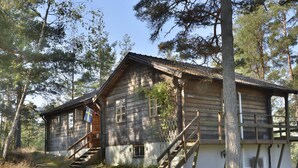 Een rustieke houten chalet met een trap naar de ingang en een vlag aan de linkerkant.