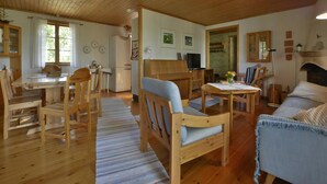 Een houten interieur met een eethoek, een bank, een televisie en een open haard.