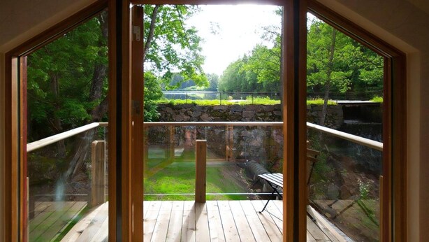 Quarto com grandes janelas que oferecem vista para um jardim e um muro de pedra.