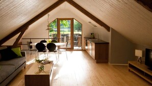 Quarto sótão com área de jantar, cozinha e espaço para sentar.