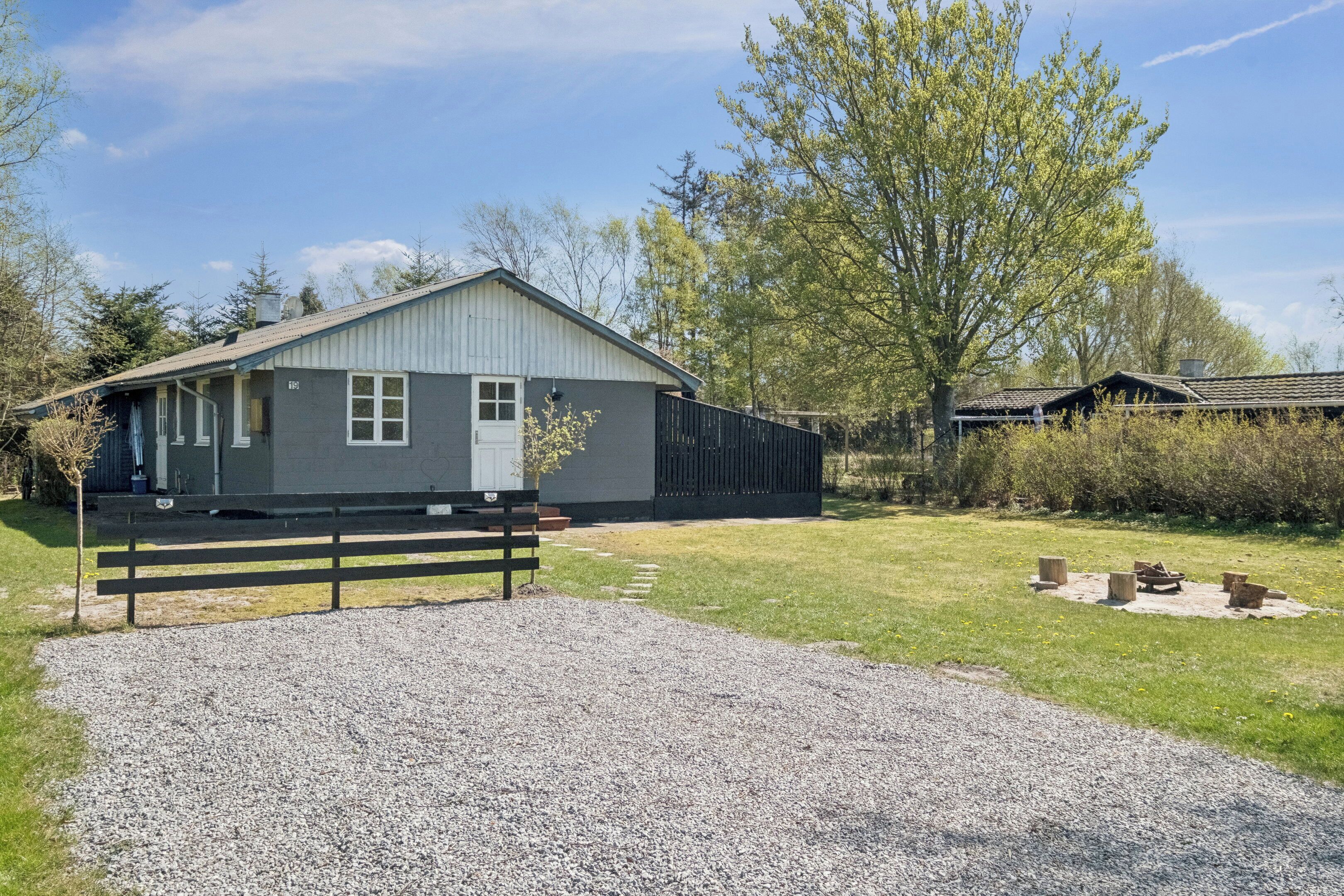 A single-story building with a gravel driveway and a wooden bench.