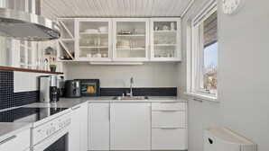 Eine moderne Küche mit weißen Schränken, einem Bosch-Ofen, einer Spüle und einem Fenster mit Blick.