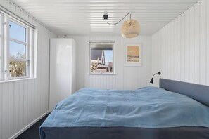 A bedroom with a bed, a window, a door, and a wall-mounted light fixture. - Holiday home for 6 near beach and Hals town (Hals)