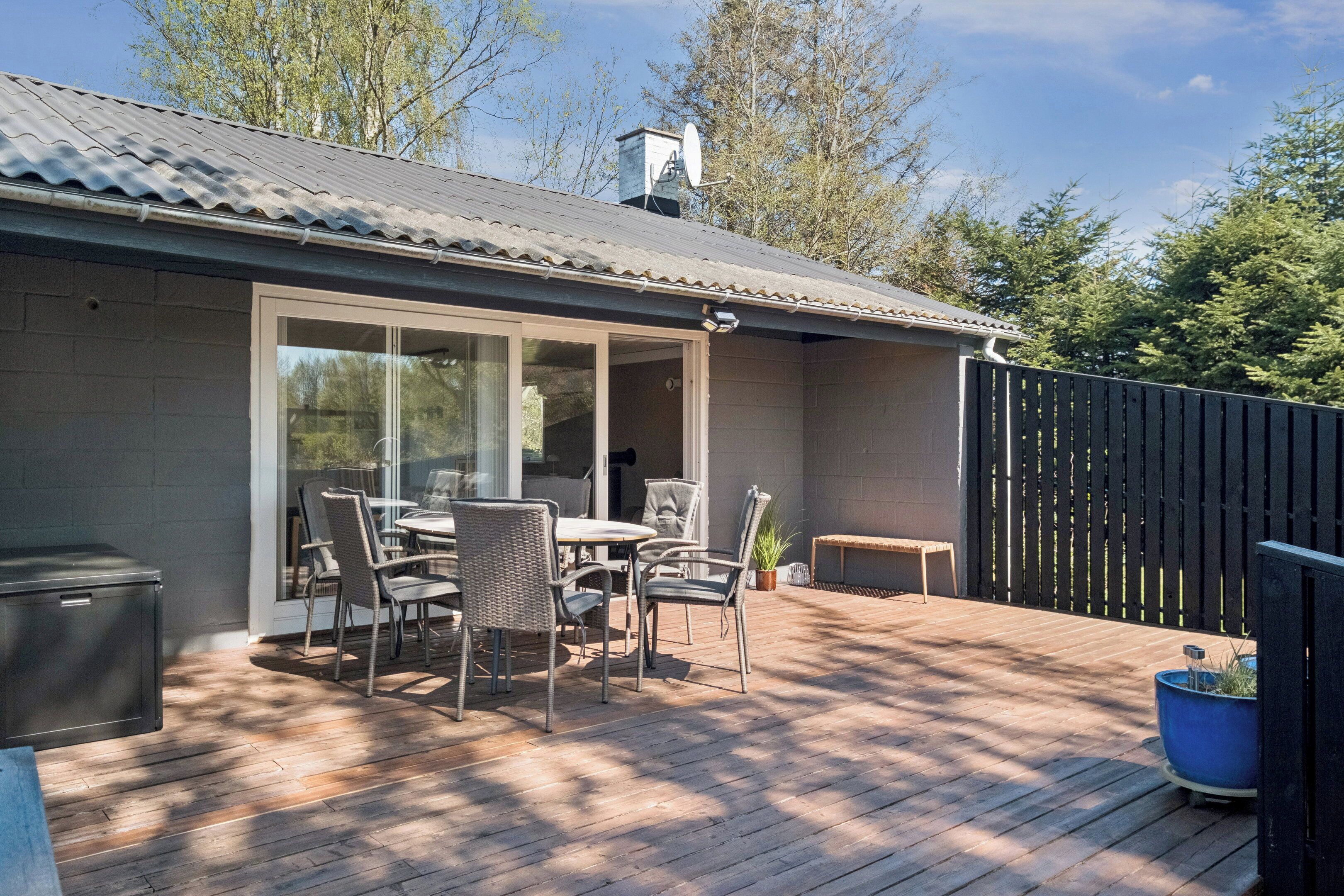 Une terrasse avec une table et des chaises, un barbecue et une plante en pot.