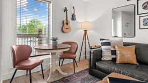 Une pièce comprenant une table à manger, des chaises, une lampe, un canapé et des guitares accrochées au mur.