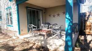 Eine überdachte Terrasse mit Tisch und Stühlen, eine Schiebetür aus Glas sowie eine Wand mit drei Sternen.