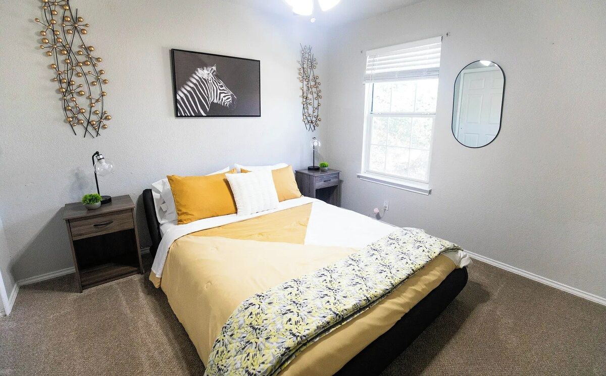 A bedroom with a bed, nightstand, lamp, and decorative wall art.