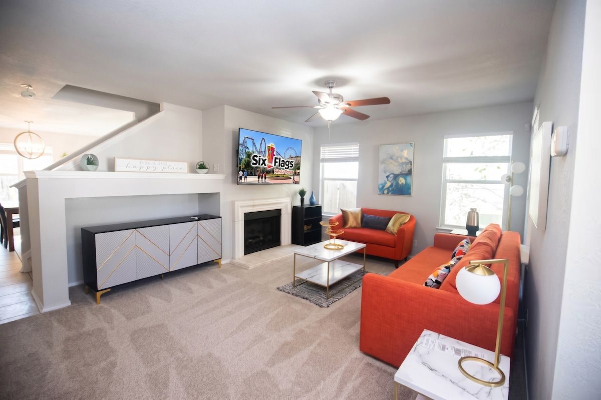 A modern living room with a fireplace, a red sofa, a coffee table, and a television mounted on the wall.