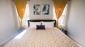 Ein Bett mit einer gemusterten Tagesdecke, zwei Kissen und Vorhängen.