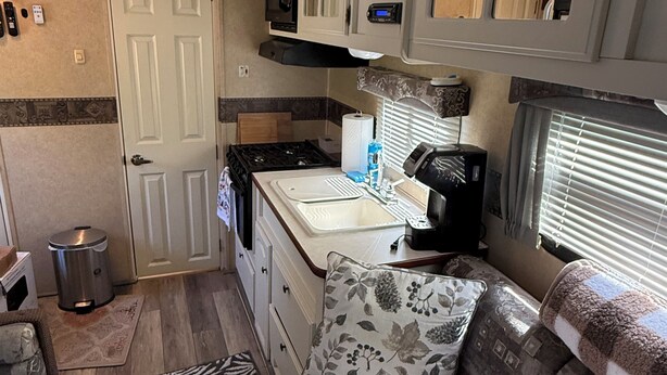 Cuina d'una autocaravana compacta amb microones, fogó, vàter i una petita finestra.