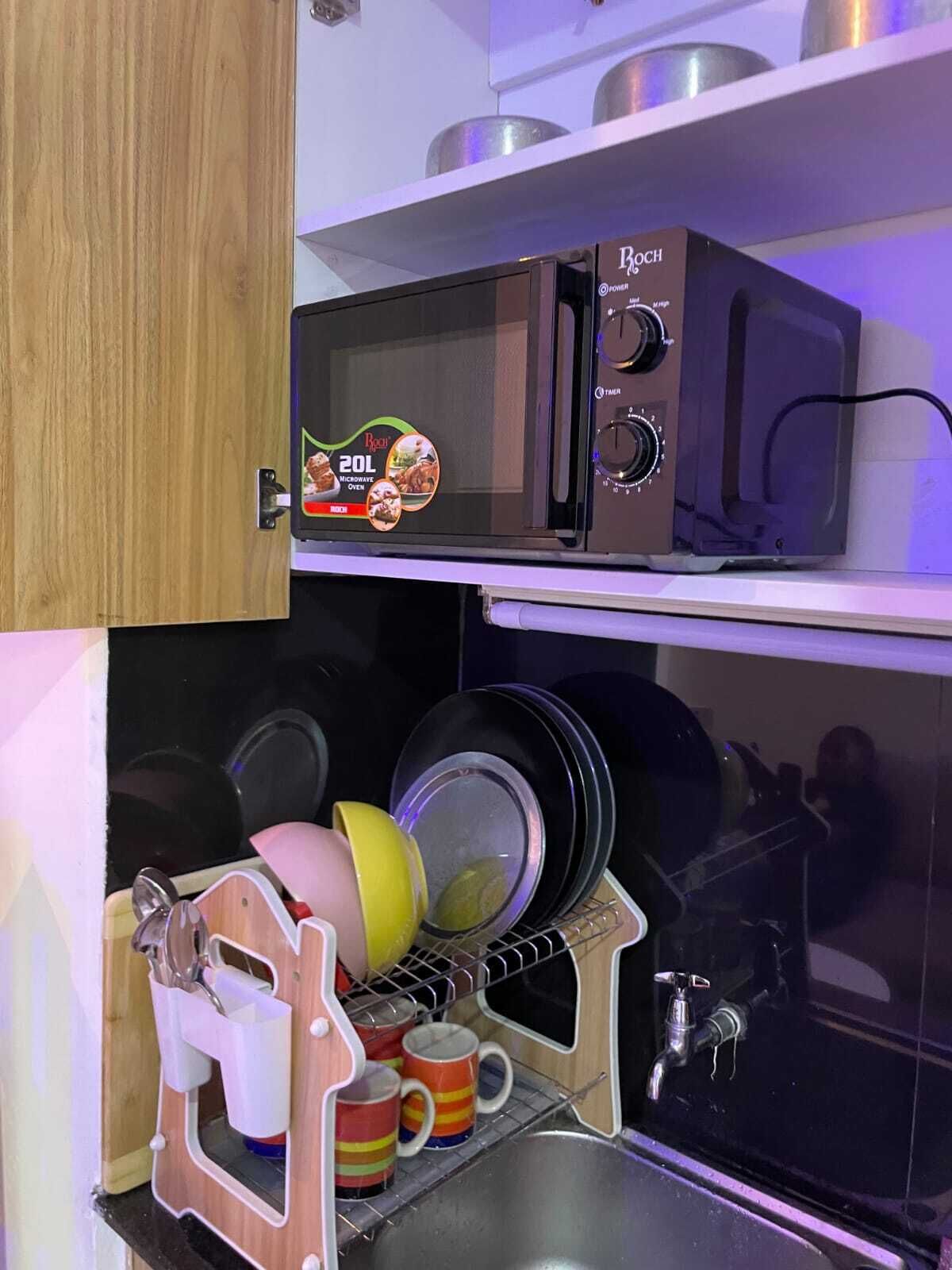 Eine Küche mit einer Bosch-Mikrowelle, einem Geschirrgestell mit Tassen und einem Spülbecken.
