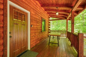 Una baita di legno con veranda, una porta e una finestra.