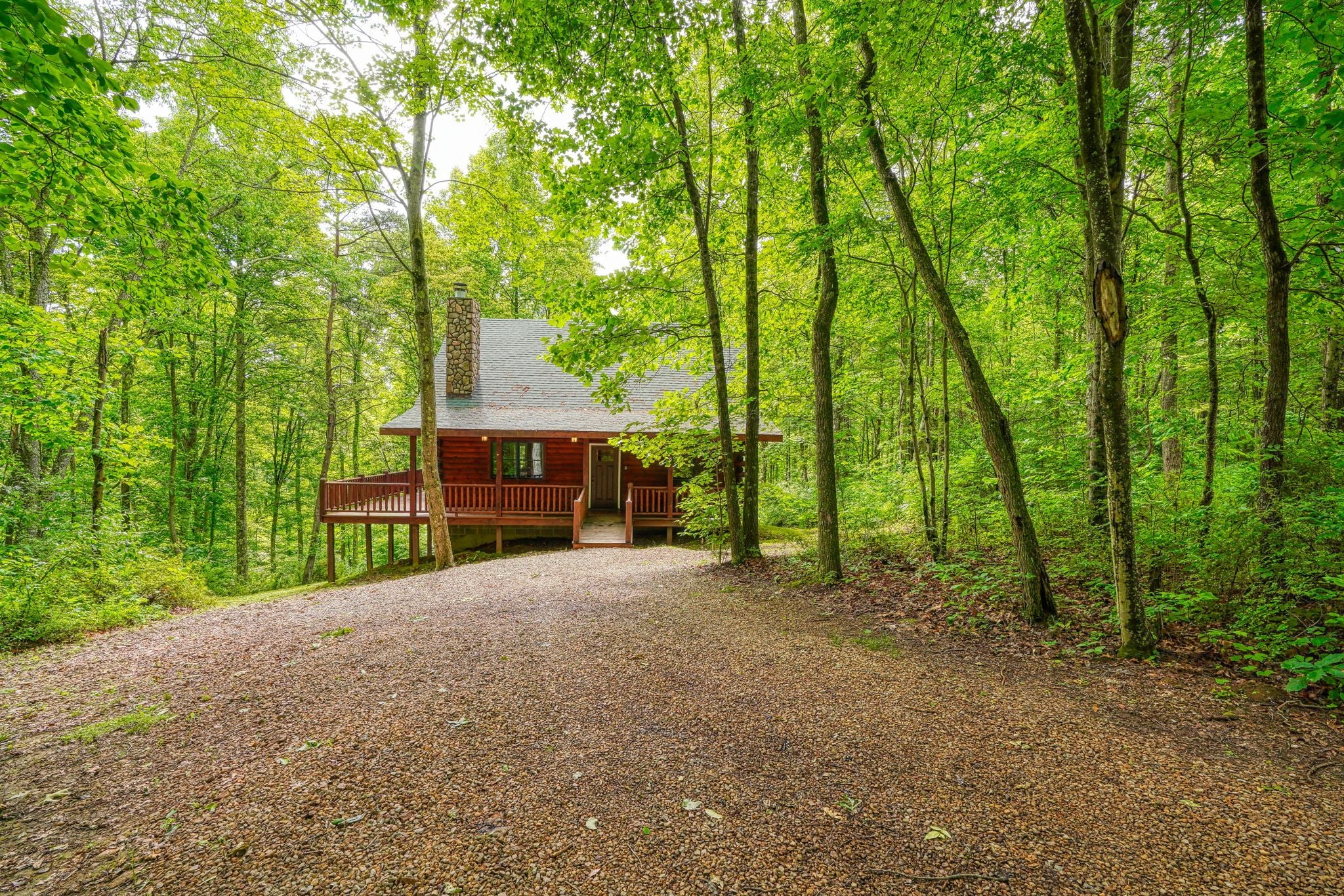 Une cabane entourée d’une forêt, avec un chemin de gravier menant à celle-ci.