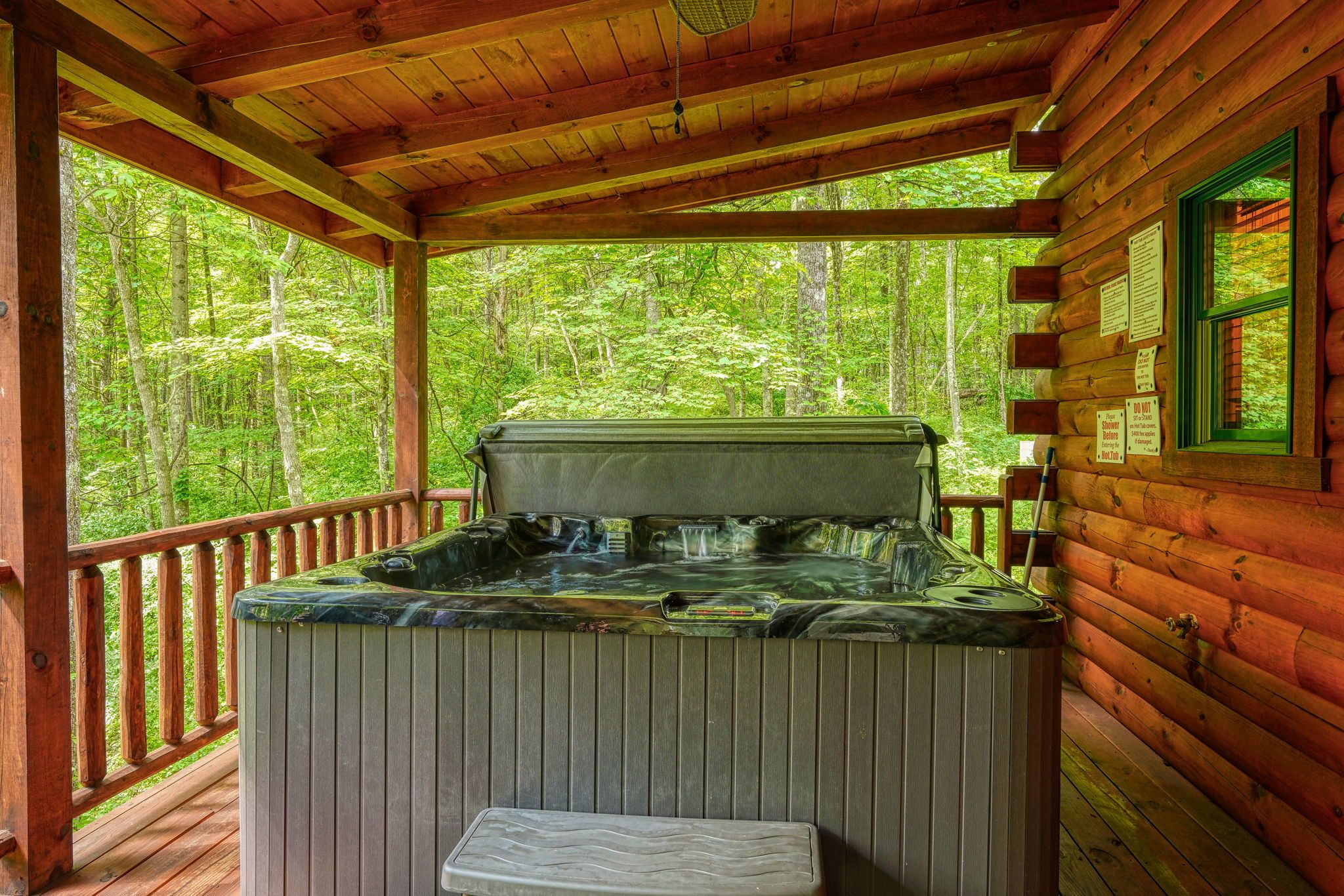 A hot tub on a wooden deck with a view of a forest.