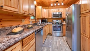 A kitchen with wooden cabinets, granite countertops, stainless steel appliances, and a wooden ceiling. - Memory Ridge Retreat, Sleeps 8, Walking Distance to Old Man's Cave (Logan)