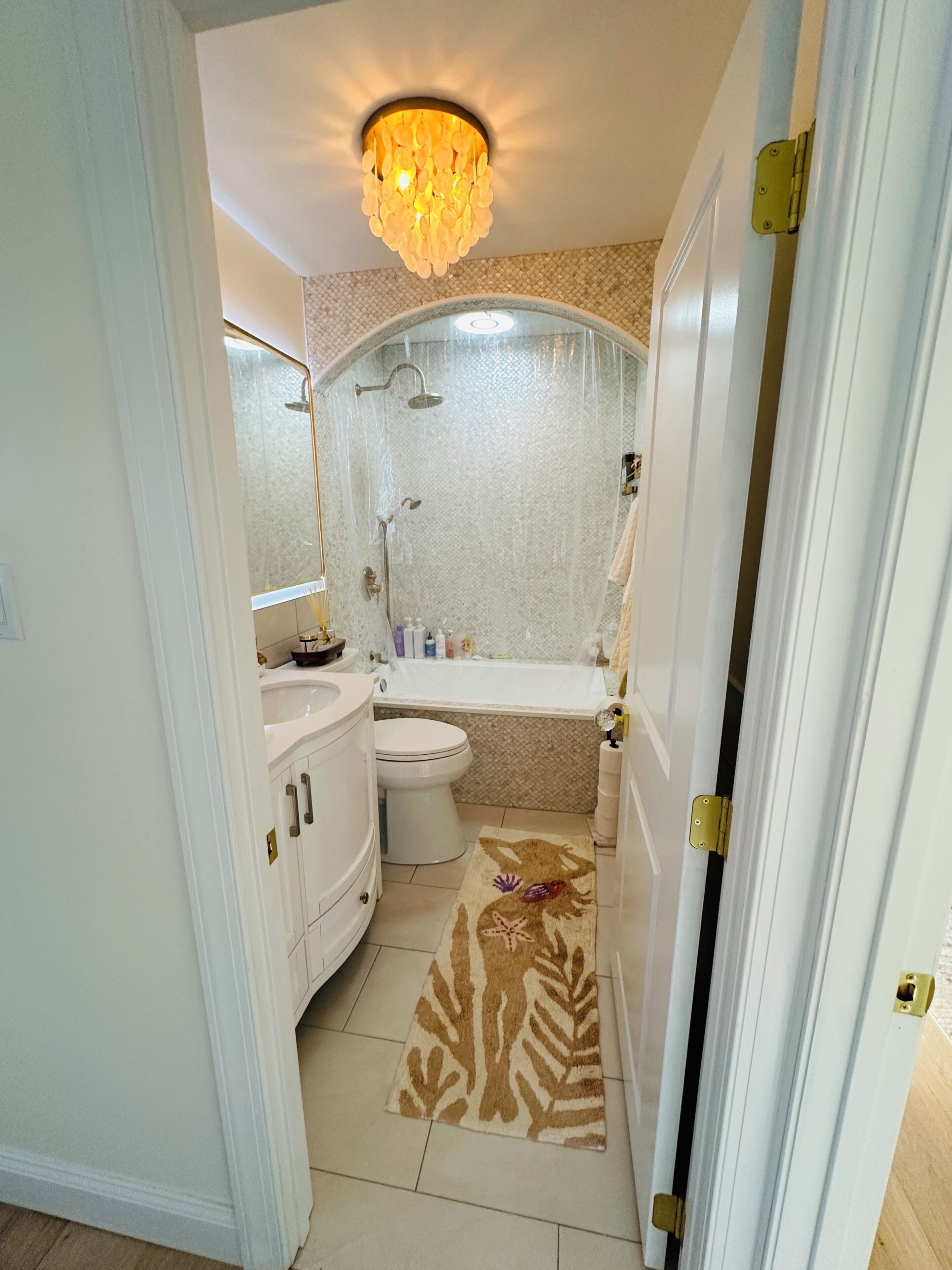 Un baño con ducha, inodoro, lavamanos y un tapete decorativo.