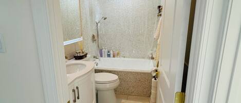 Un baño con ducha, inodoro, lavamanos y un tapete decorativo.