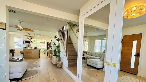 A spacious living area with a staircase, a kitchen, and a dining area. - Sandy Buns Bungalow Beach House Escape (Ventnor City)
