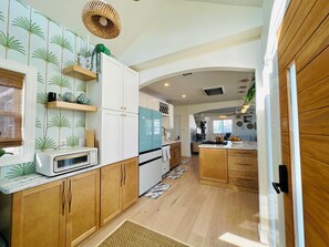 A kitchen with wooden cabinets, a white refrigerator, and a blue stove. - Sandy Buns Bungalow Beach House Escape (Ventnor City)