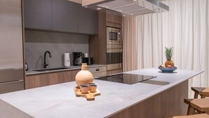 Cozinha moderna com ilha central, eletrodomésticos de aço inoxidável e bancada de madeira.