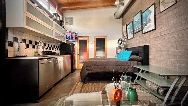 A compact room with a kitchenette, a bed with a headboard, a TV mounted on the wall, and a ceiling fan. - Mid Century Modern Casita, kitchenette, laundry, AC & pool in Uptown Phoenix (Phoenix)