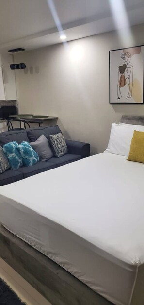 A bedroom with a bed, a sofa, a small table, and a wall-mounted artwork. - Studio with private deck (Portmore)