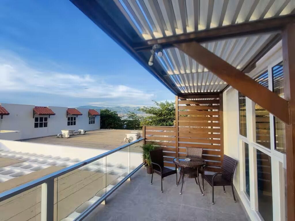 A balcony with a view of buildings, a wooden fence, and a table with chairs.