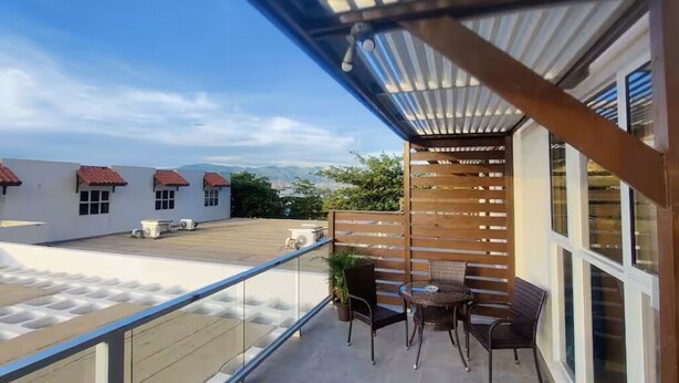 A balcony with a view of buildings, a wooden fence, and a table with chairs. - Studio with private deck (Portmore)