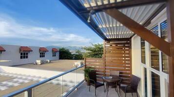 A balcony with a view of buildings, a wooden fence, and a table with chairs.