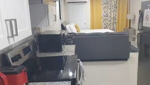 A compact hotel room with a kitchenette, a bed, and a refrigerator. - Studio with private deck (Portmore)