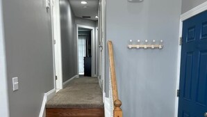 A hallway with a wooden staircase, a blue door, and a coat rack. - Family Beach Getaway – Walk to Beach, Boardwalk & Enjoy Coastal Comfort (Ocean City)