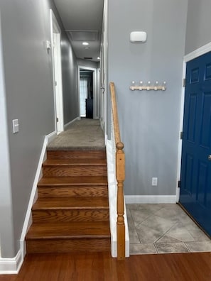 Ein Flur mit einer Holztreppe, einer blauen Tür und einem Garderobenschrank.