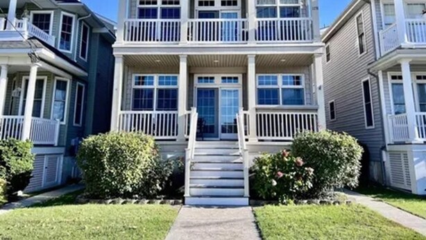 A two-story residential building with a front porch, a staircase leading to the entrance, and a well-maintained lawn. - Family Beach Getaway – Walk to Beach, Boardwalk & Enjoy Coastal Comfort (Ocean City)
