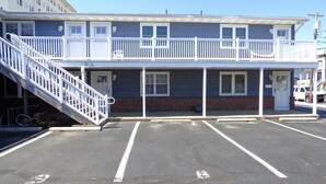 A two-story building with a balcony, a staircase, and a parking lot. - Bright & Welcoming 2BR Near Beach, Boardwalk & Local Attractions (Ocean City)