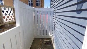 A narrow wooden deck with a white fence, a metal gate, and a metal vent on the siding. - Bright & Welcoming 2BR Near Beach, Boardwalk & Local Attractions (Ocean City)